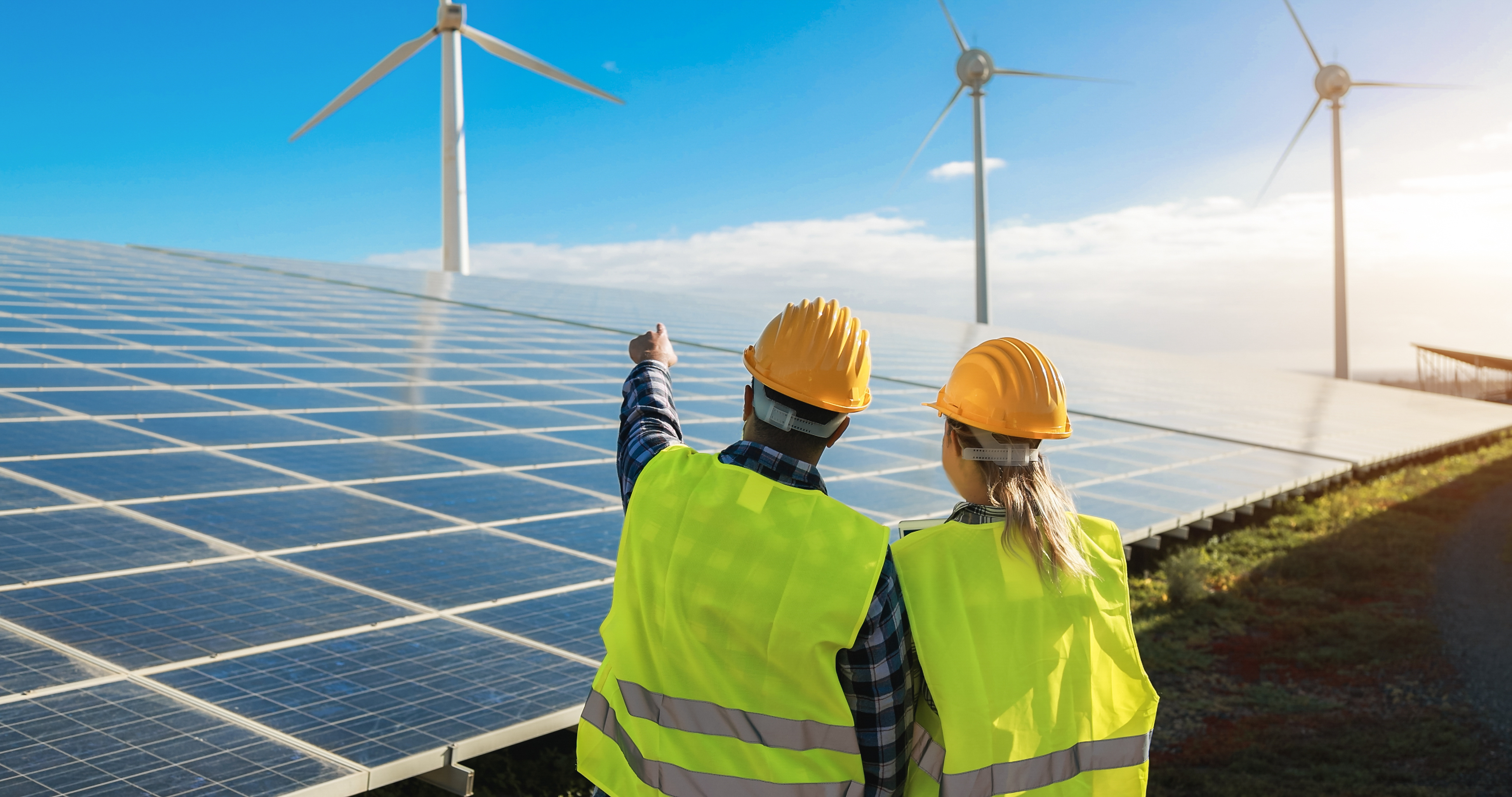 Standaardafbeelding: 2 werkmensen die wijzen naar een windmolen op een zonnepanelenplatform